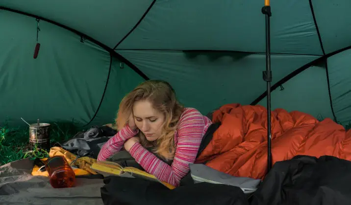 Woman reading in a tent.